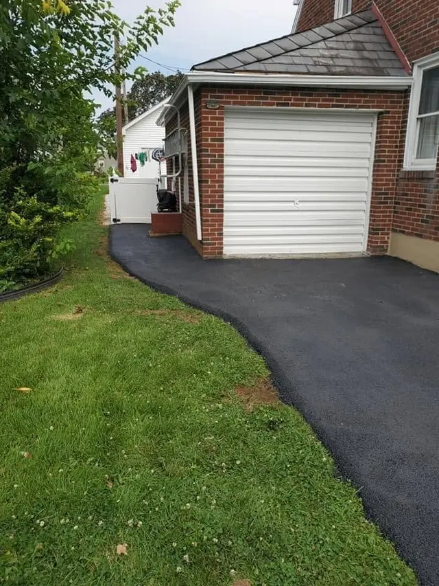 Jet-black sealed driveway beside a green lawn